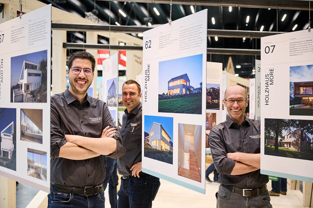 Mitarbeiter zwischen Referenzen auf com:bau Messestand 2022